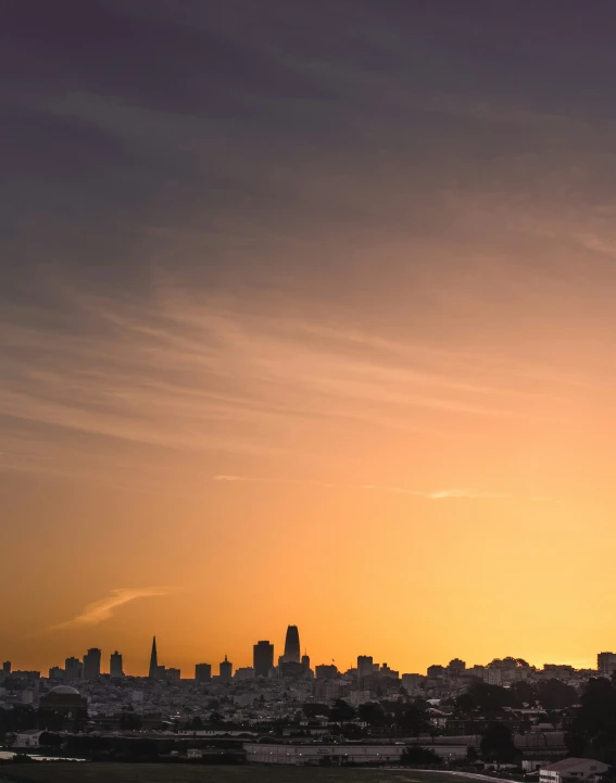 a city skyline with the sun setting over it