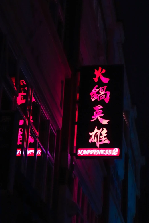 a lit up sign hanging off the side of a building