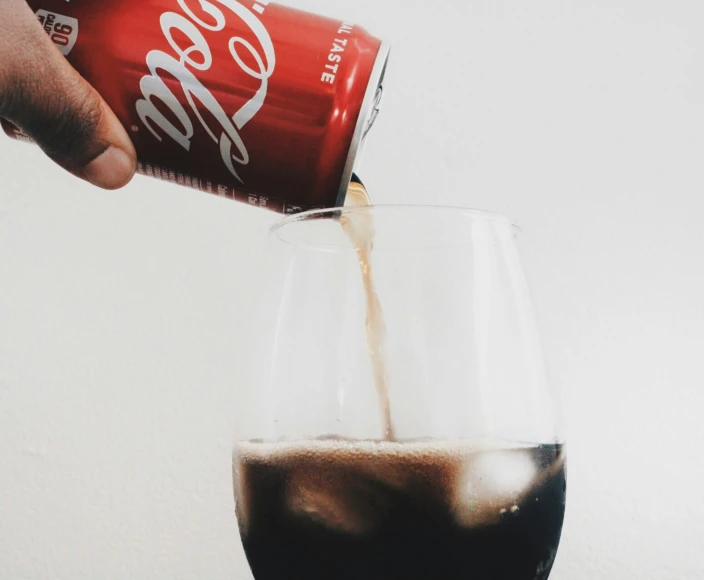 someone pouring coke into a wine glass
