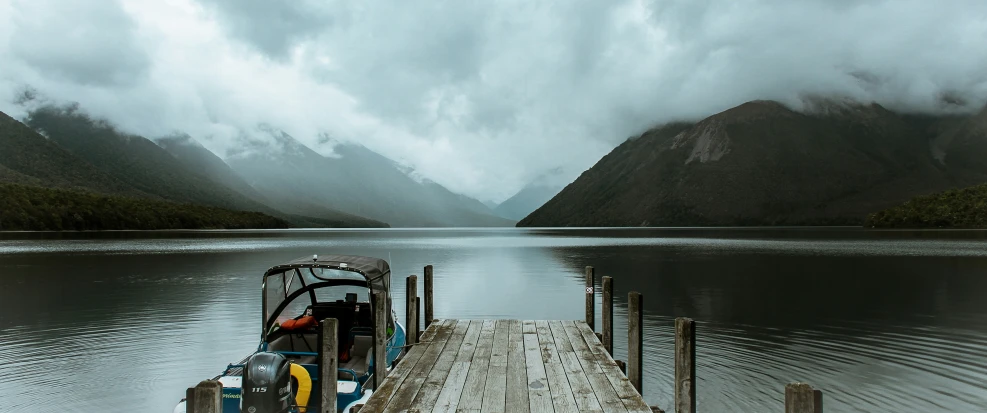 a boat sits at a pier overlooking a body of water with mountains in the background