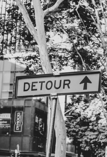 a street sign for detour is pointing towards the right