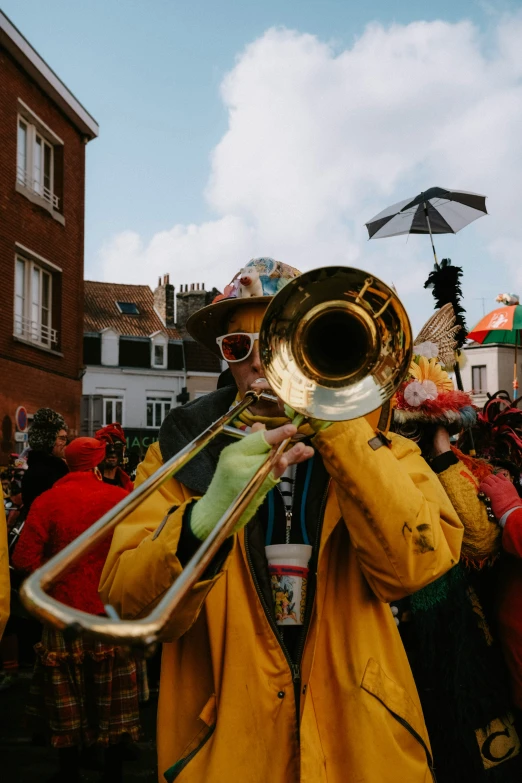 a man wearing a raincoat and sunglasses playing a trombone
