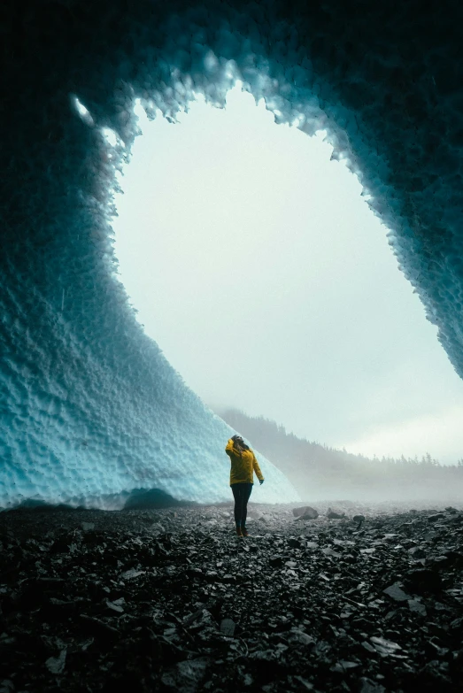 man in large blue ice cave holding a light saber