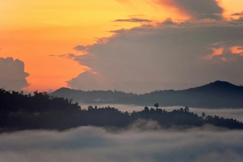 the sunrise over clouds and mountain tops on a misty day