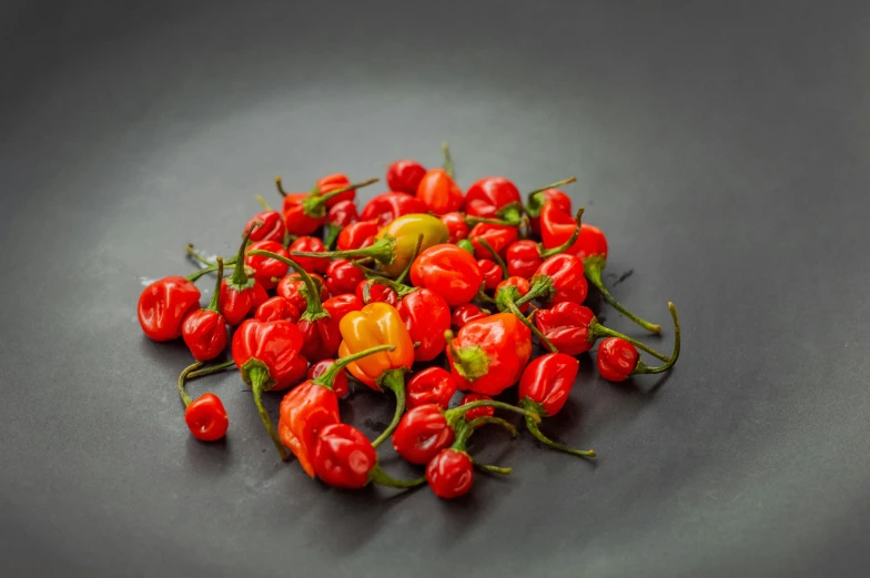 a bowl full of red  peppers with green stems