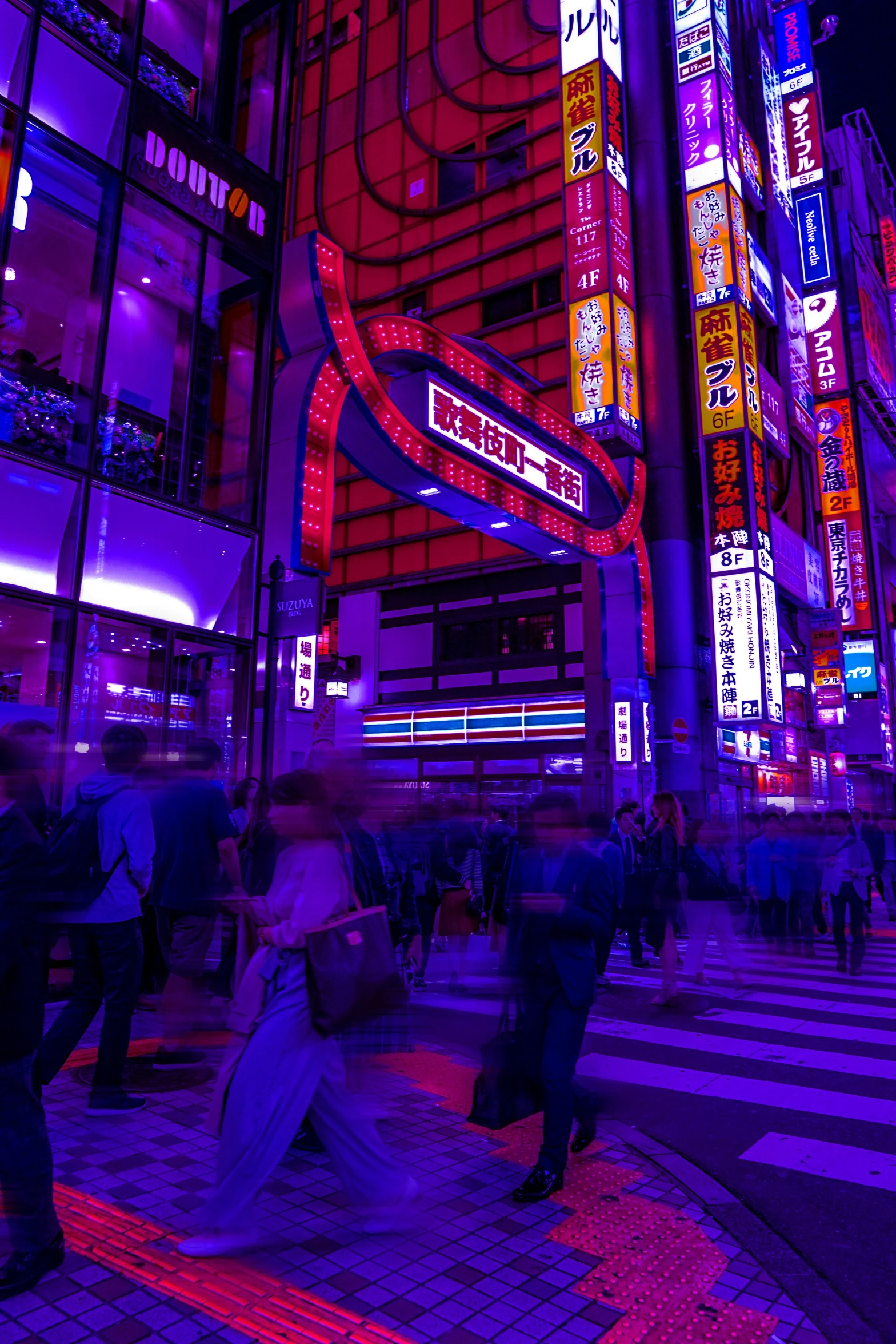 people crossing the street at night with tall building lights in the background