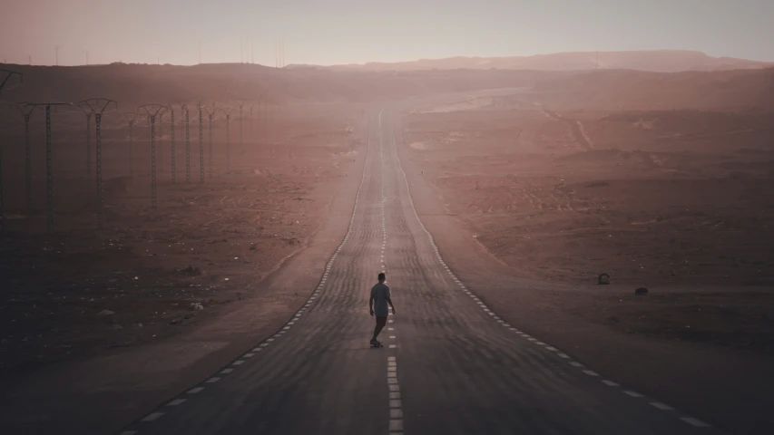 man on road near barren hill in late afternoon