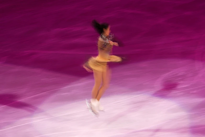 a female figure skating on a rink indoors