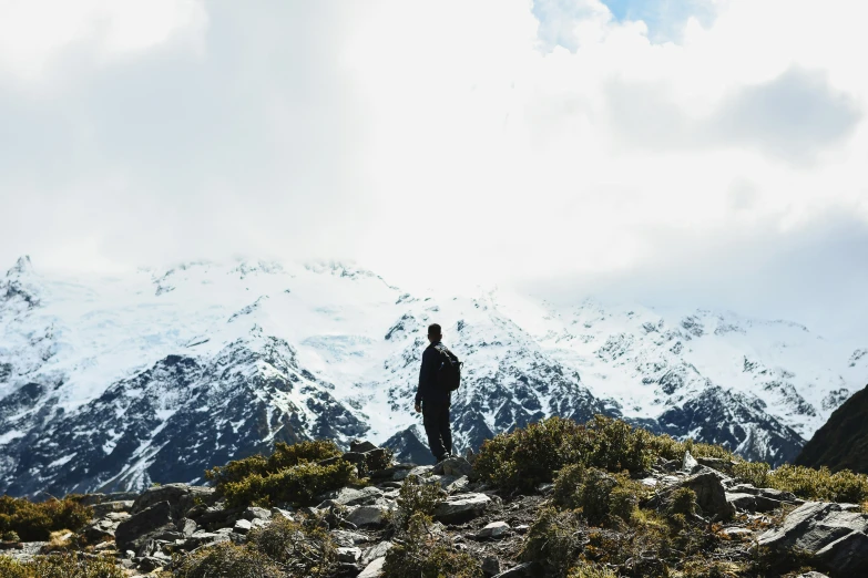 a man looking up at a mountain with snow on the top