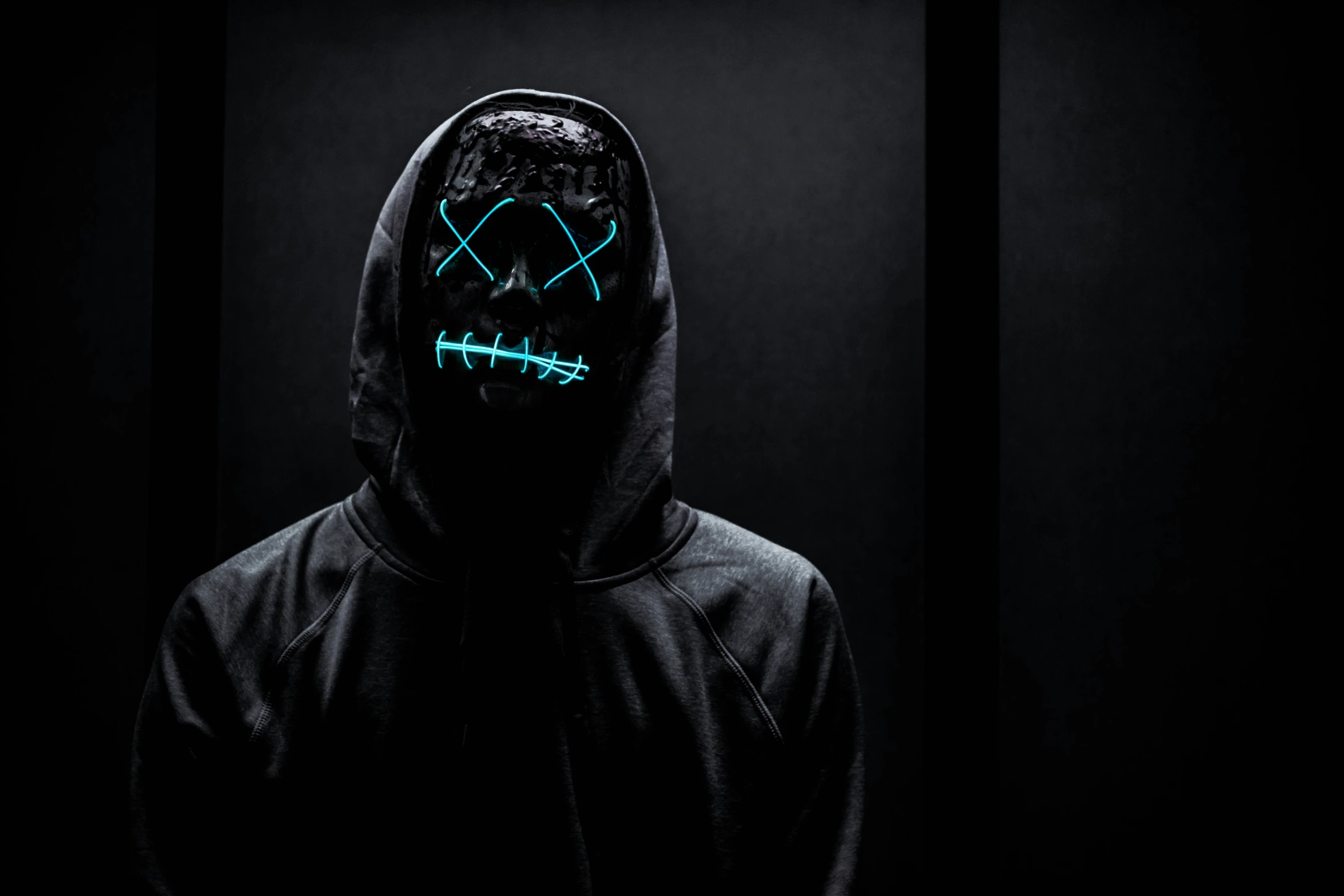 someone in the dark with a hood and glow mask