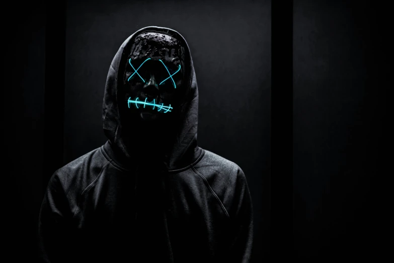 someone in the dark with a hood and glow mask
