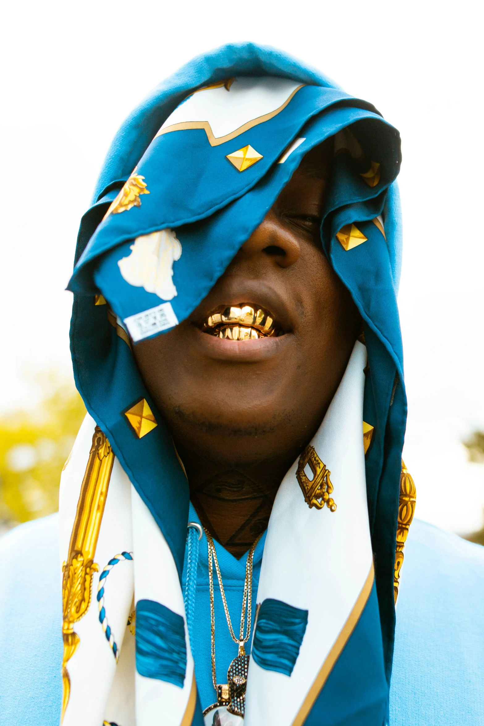a man in a blue shirt wearing some gold chains