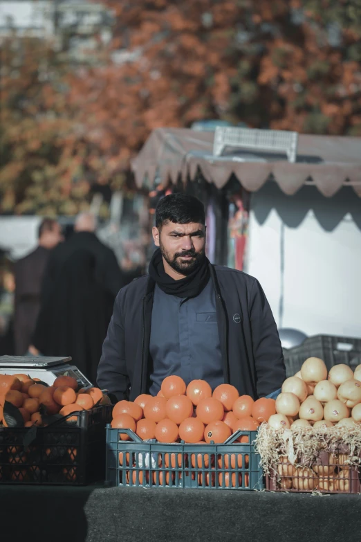 a man standing in front of a variety of fruits