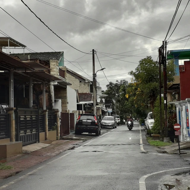 two people walk down an urban street, one car is seen driving past