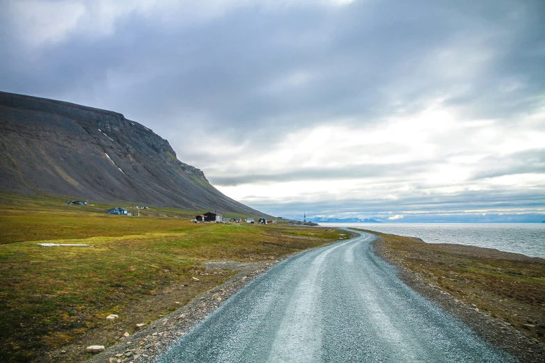 the road runs beside the sea under a dark cloudy sky