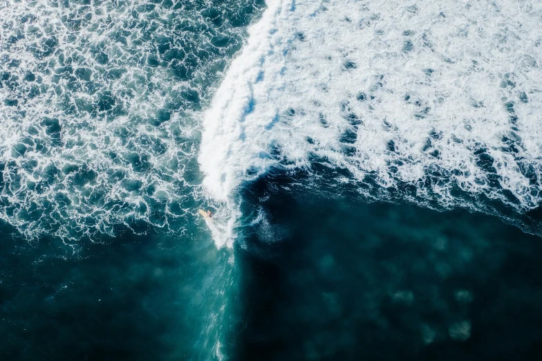 an overhead view shows water and a surfboard coming towards the horizon