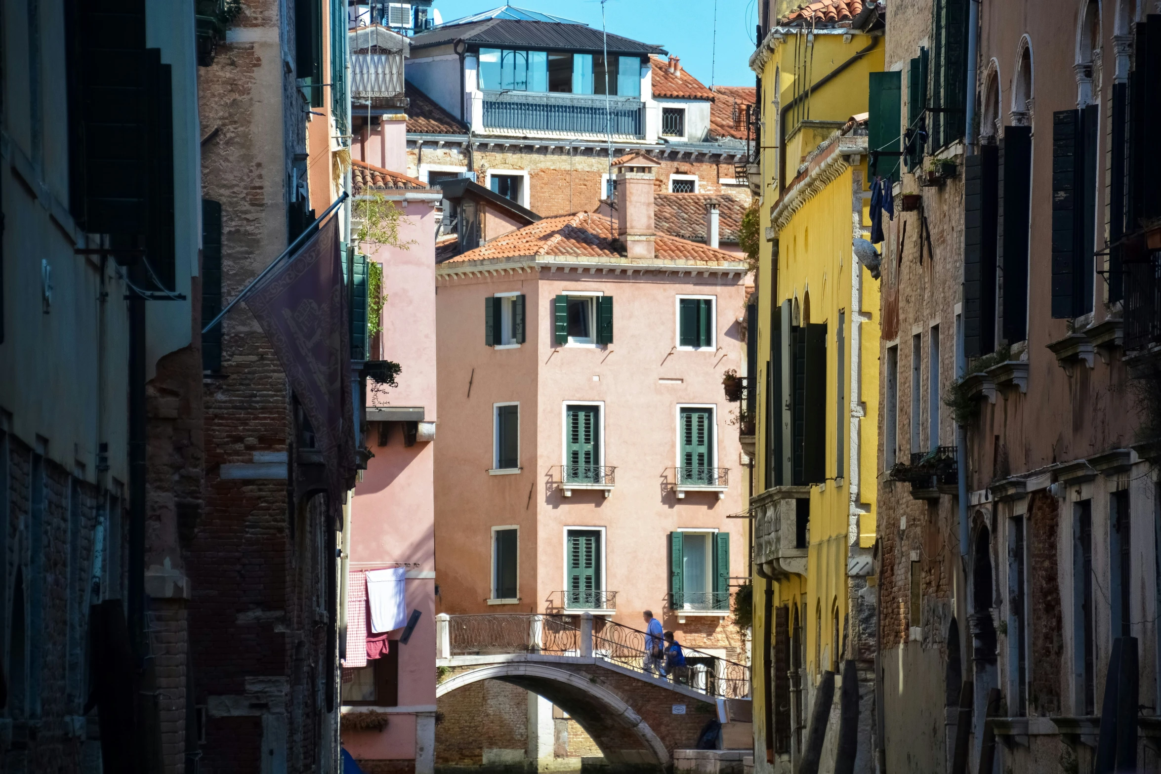 a narrow city street with multiple building and a bridge