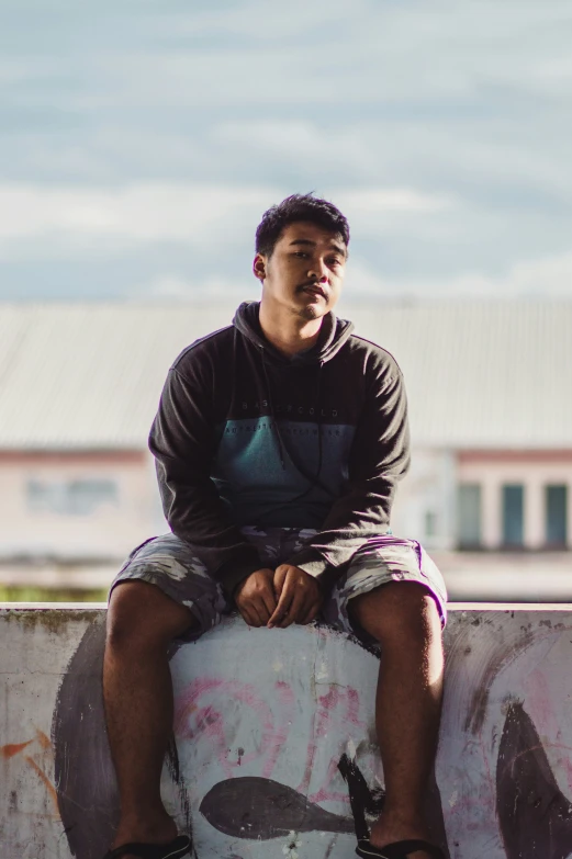 the young man is sitting on his skateboard outside