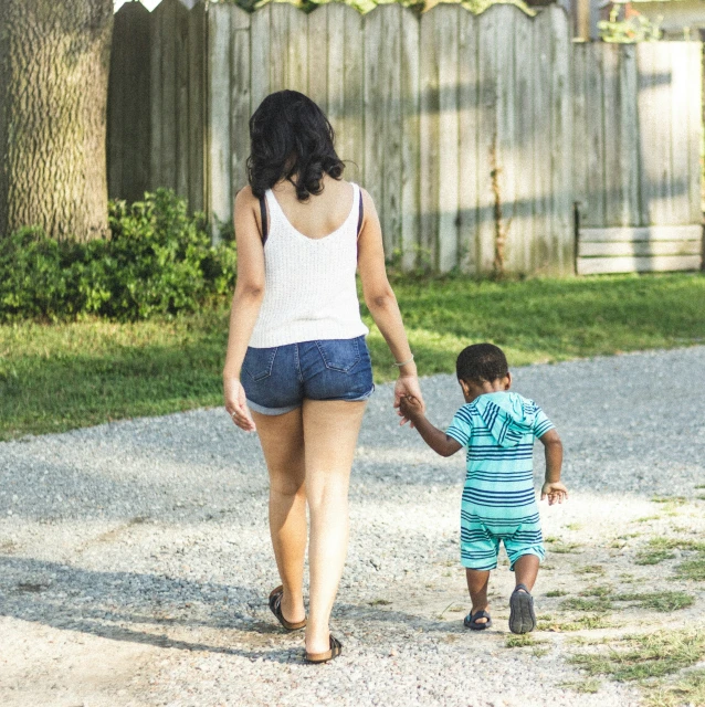 a girl in a white tank top holding onto a boy's hand