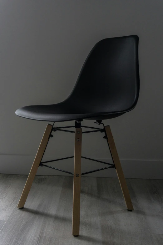 a chair with wooden legs in front of a white wall