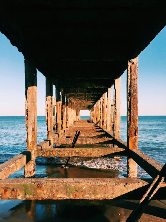 the underside of a pier next to the ocean