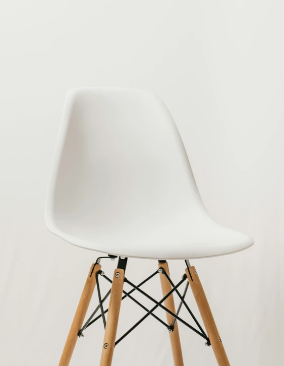 a white eames chair with wooden legs on a plain background