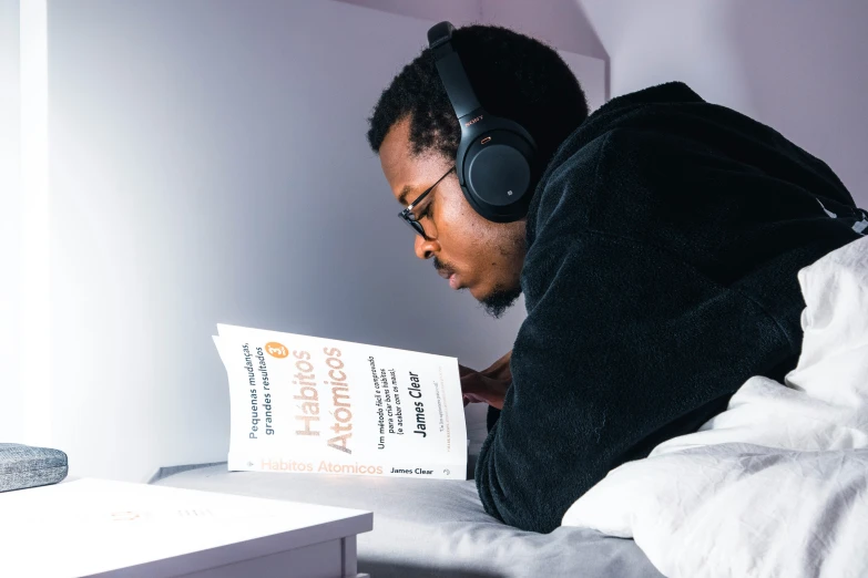 a man wearing headphones and reading a book