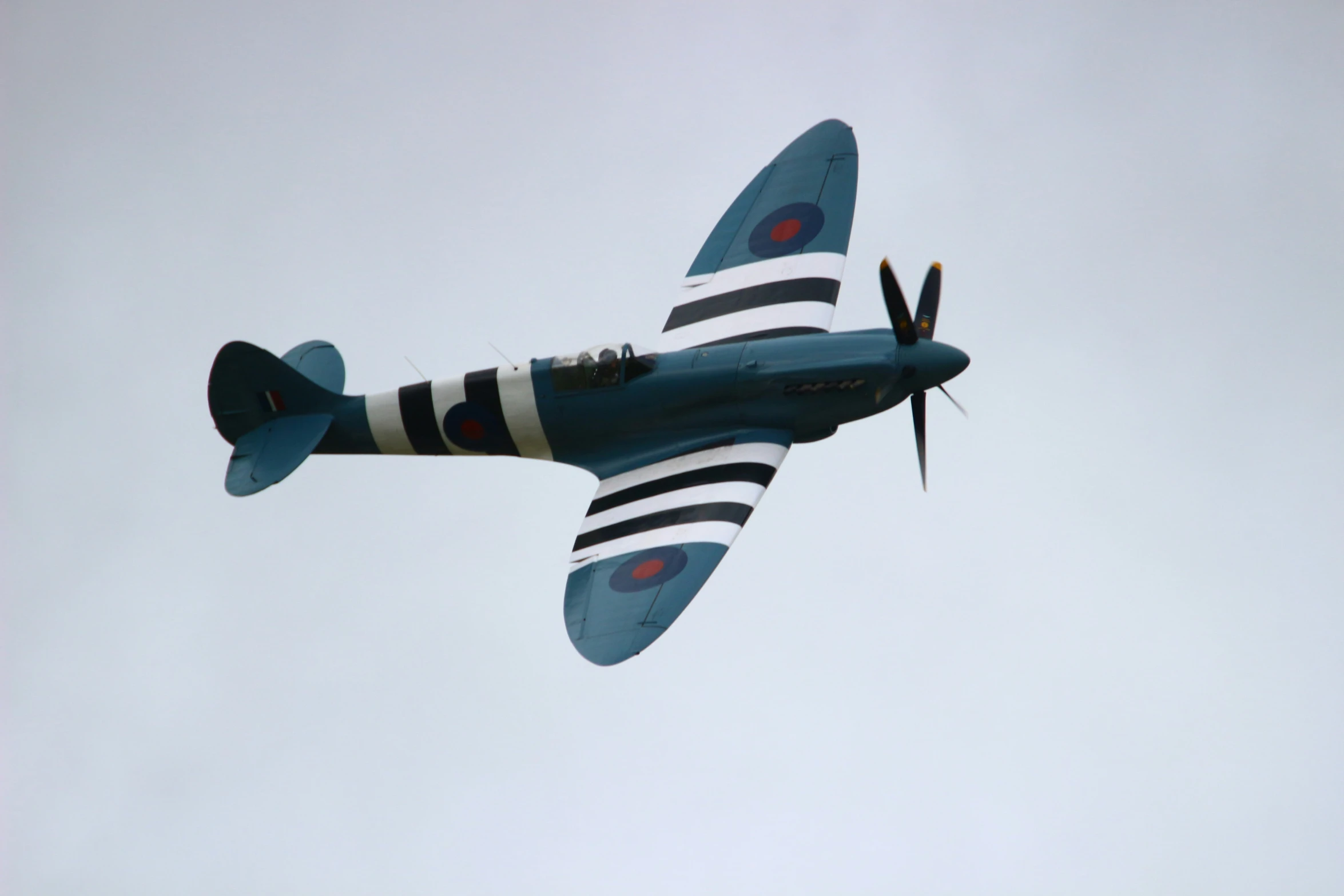 a blue propeller airplane flying through a cloudy sky