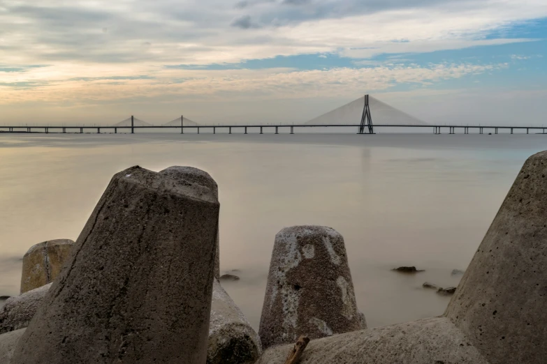 a long bridge spanning over the water from rocks