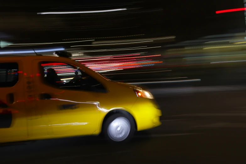 a yellow taxi driving down a street at night