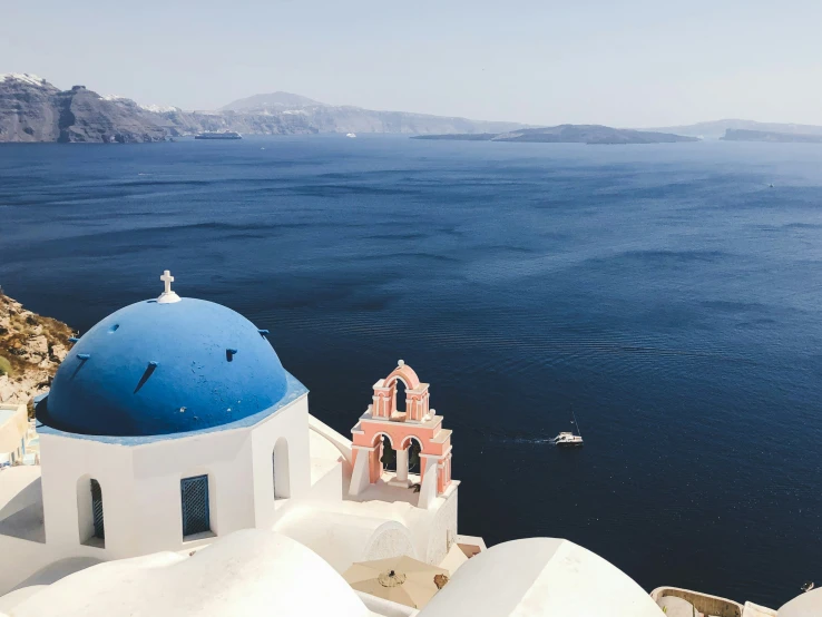 a blue and white church on top of a building next to a lake