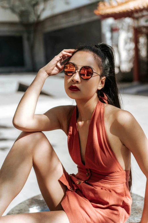 a young woman in an orange dress sits down and looks off to the right