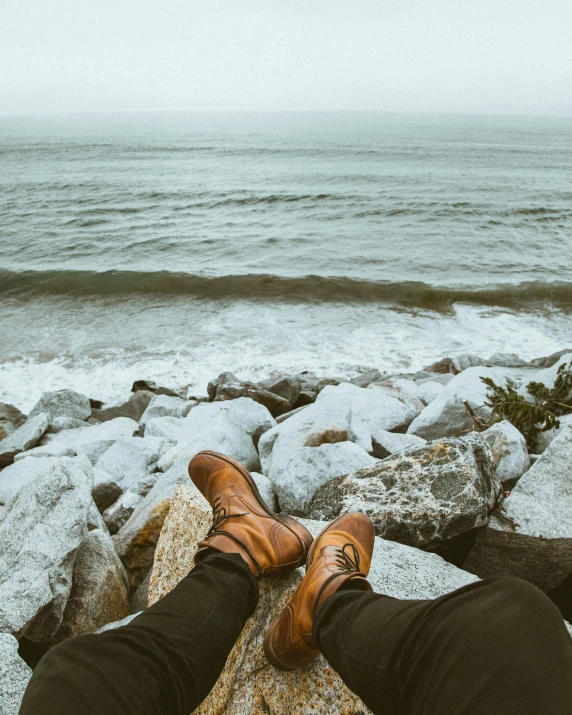 a person sitting on rocks overlooking a body of water