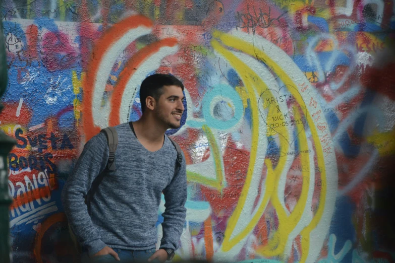 a man standing next to a wall covered in graffiti