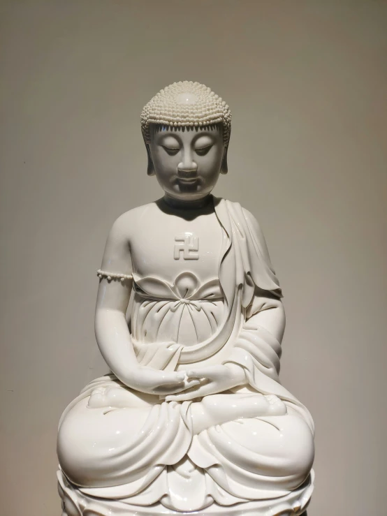 a white buddha statue sitting on a small pedestal