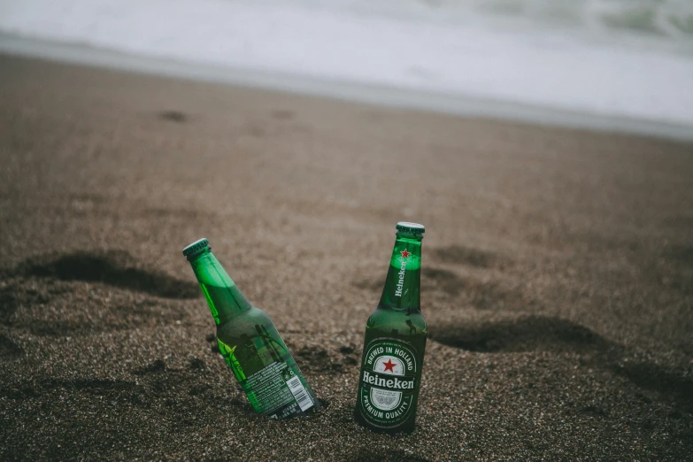 two beer bottles that are sitting in the sand