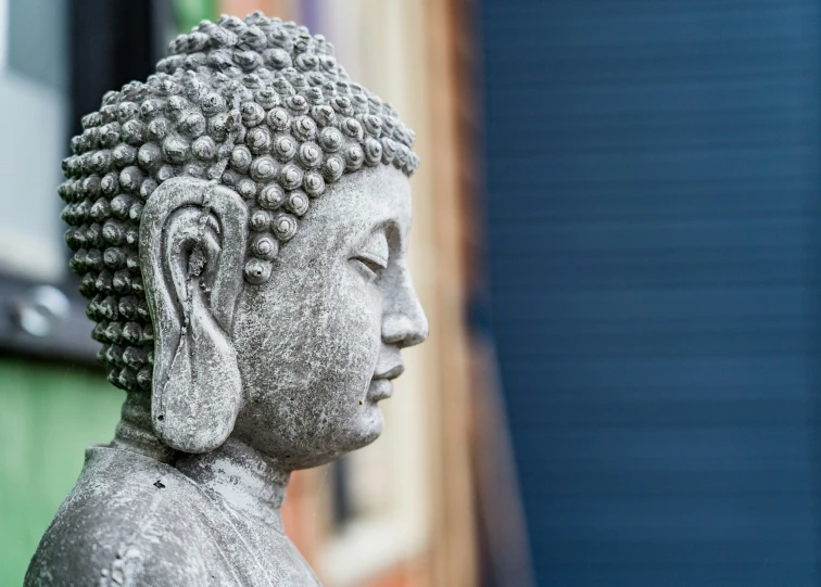 small buddha statue in front of a green wall