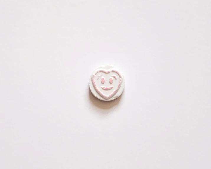 a white heart pin with a red smiley face