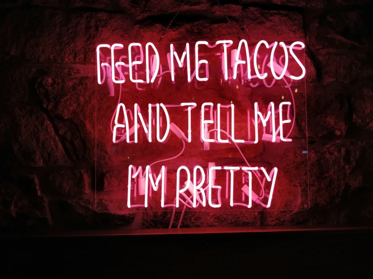a neon sign that says feed me tacos and tell me i'm archery