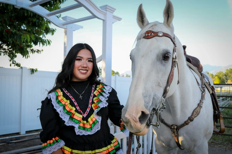 woman in traditional mexican clothing next to white horse