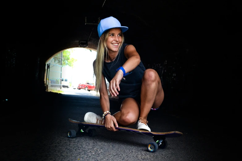 a woman crouching on her skateboard inside a tunnel