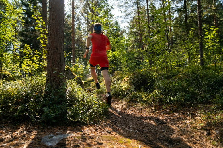 a man wearing red shorts is riding on a trail through the woods