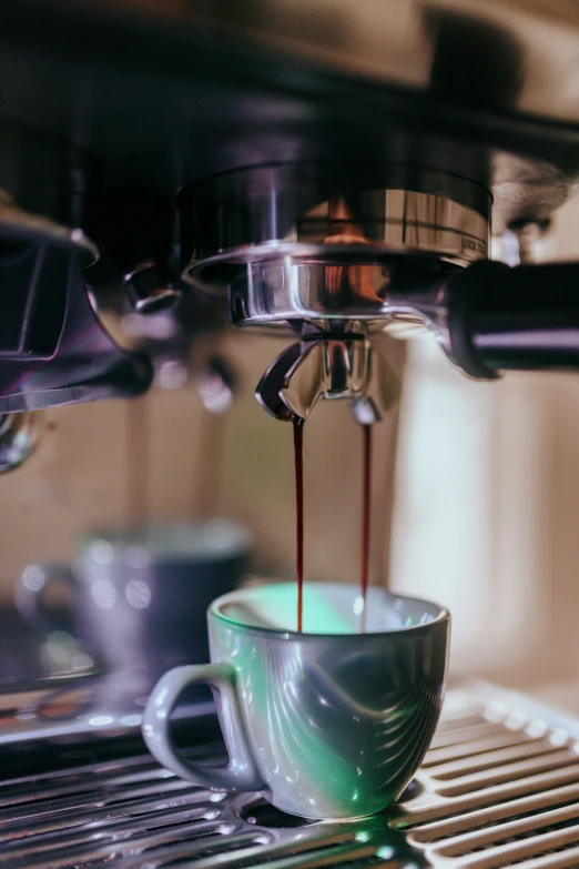 a coffee cup on the espresso machine with coffee being poured from it