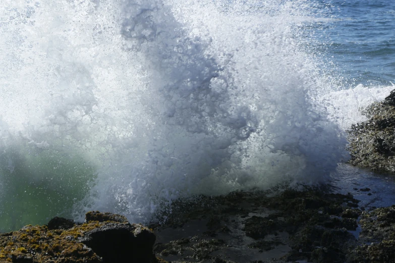 a wave crashing over some rocks in the water