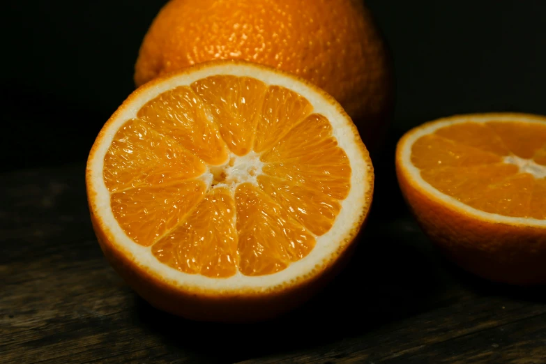 two halves and an orange sitting on a wooden table