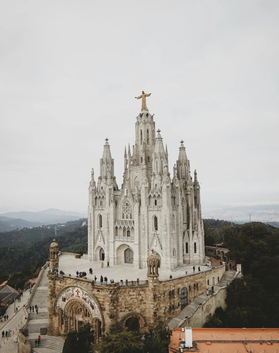 the statue on top of this large church is overlooking a landscape