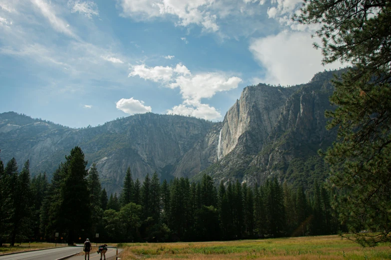 some people that are standing in the grass and a mountain