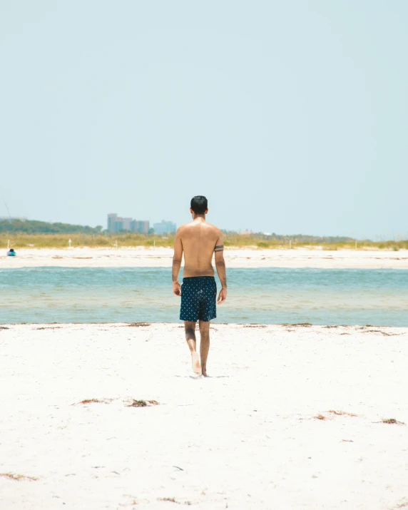 man walking on beach with surfboard in background