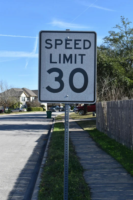a speed limit sign is by a grassy curb