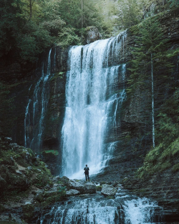 two people standing at the base of a waterfall